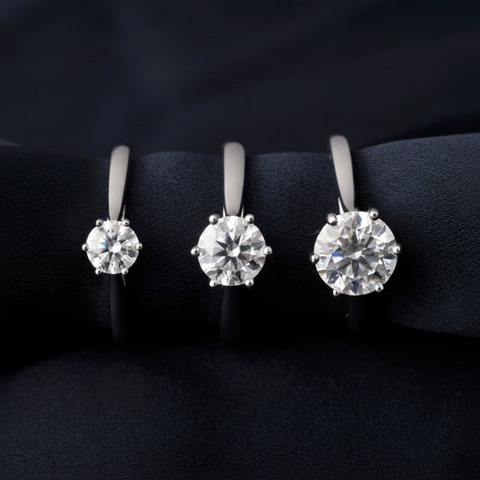 Three different sizes of moissanite rings on a black background