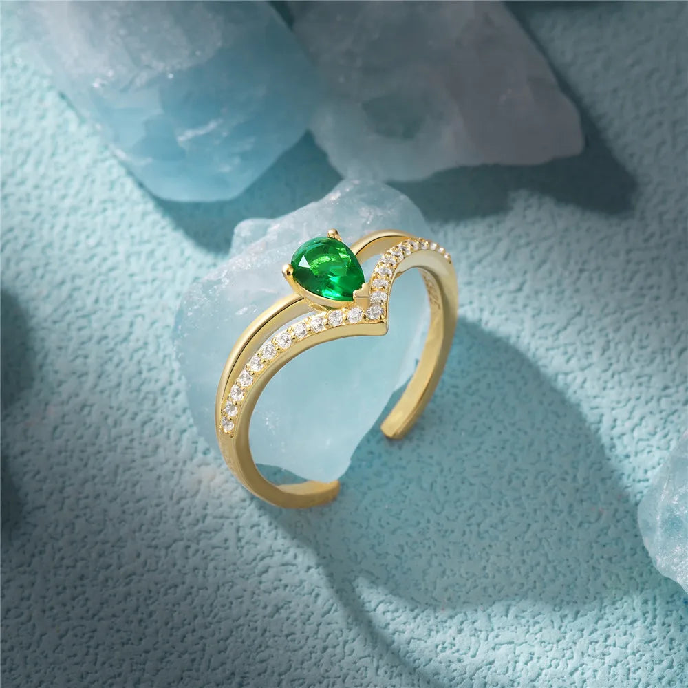 A stunning gold ring with a pear-shaped green cubic zirconia, sparkling under soft lighting.