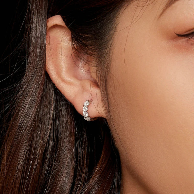 Sterling silver huggie hoops with moissanite stones reflecting light beautifully.