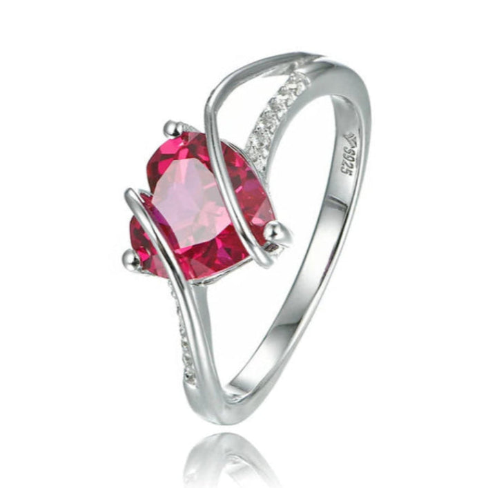 A stunning silver ring featuring a heart-shaped ruby centerpiece and white side stones.
