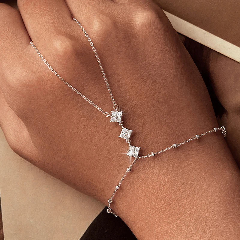 Silver bracelet with star-shaped charms on a wrist against a neutral background