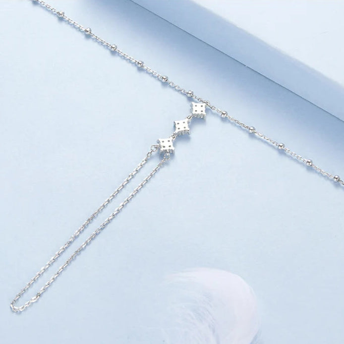 Silver hand chain bracelet on a light blue background