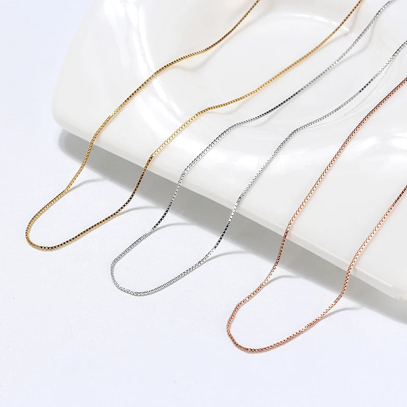Collection of silver, gold, and rose gold box chains displayed together.