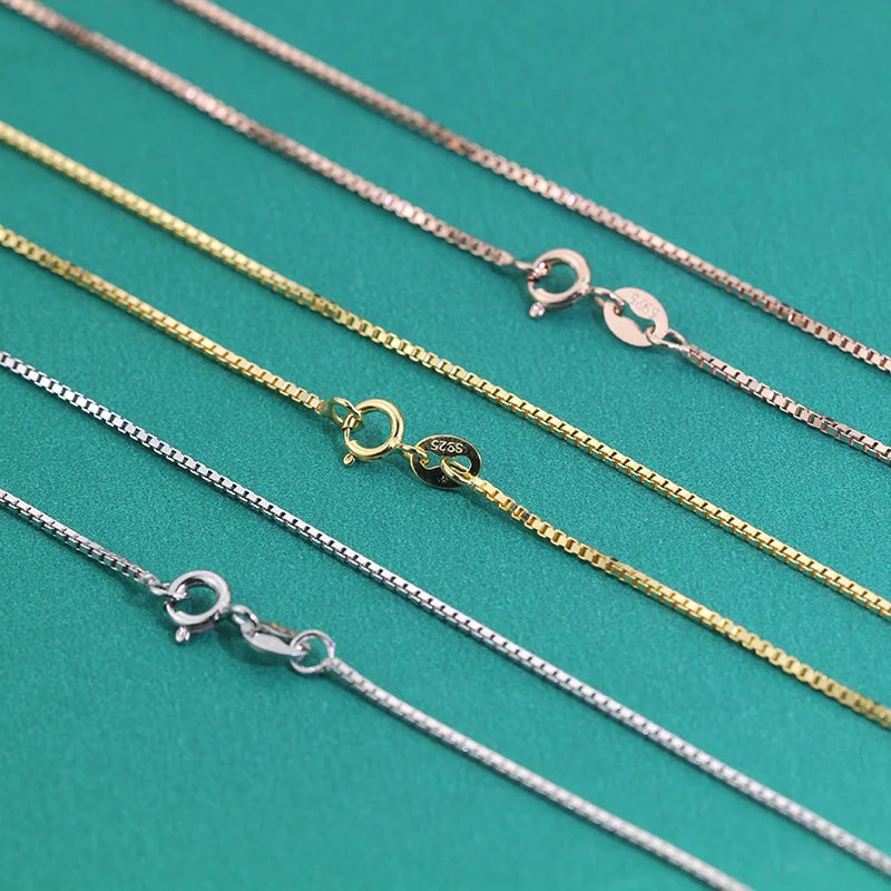 Close-up of silver, gold, and rose gold box chains showing spring ring clasps side by side.