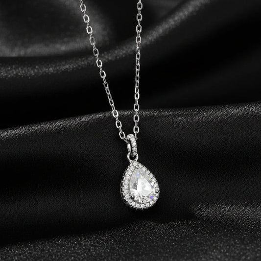 Signature Moissanite pear halo pendant displayed on draped black silk to highlight the rhodium finish