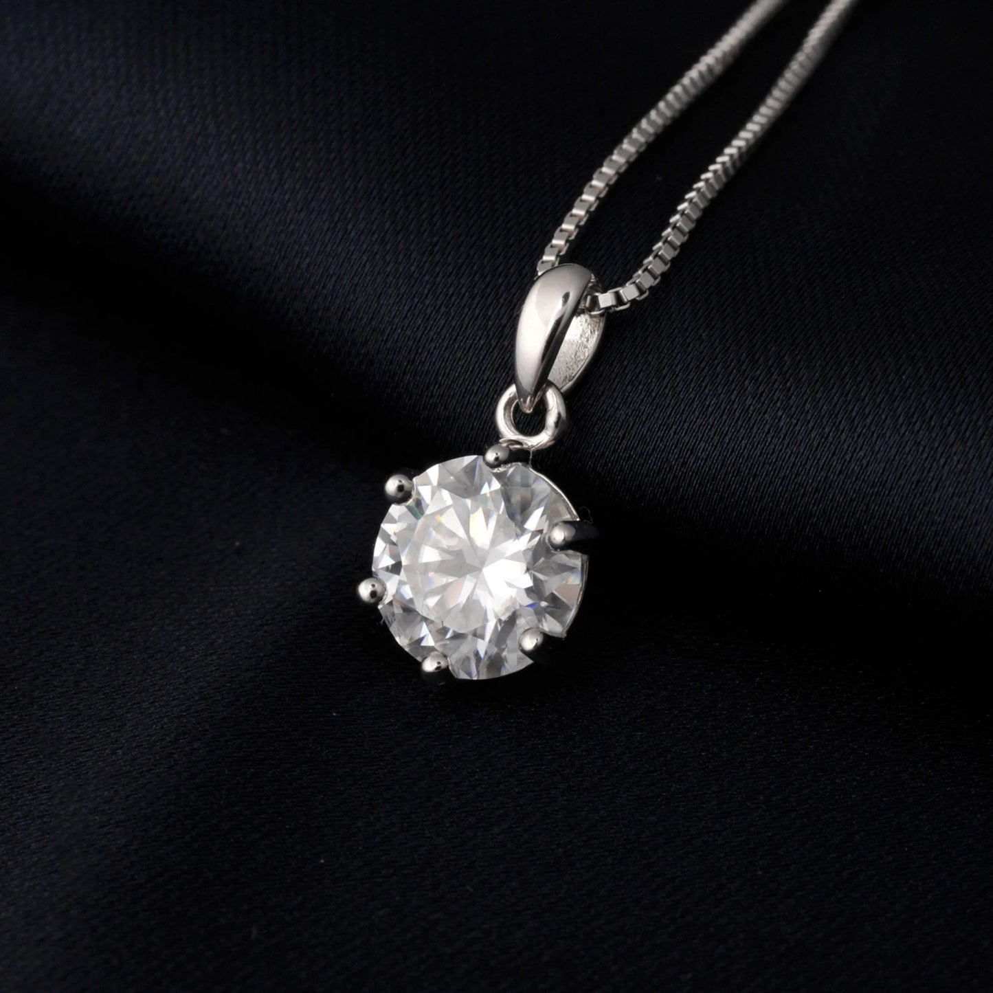 Silver necklace with a round moissanite pendant on a black background