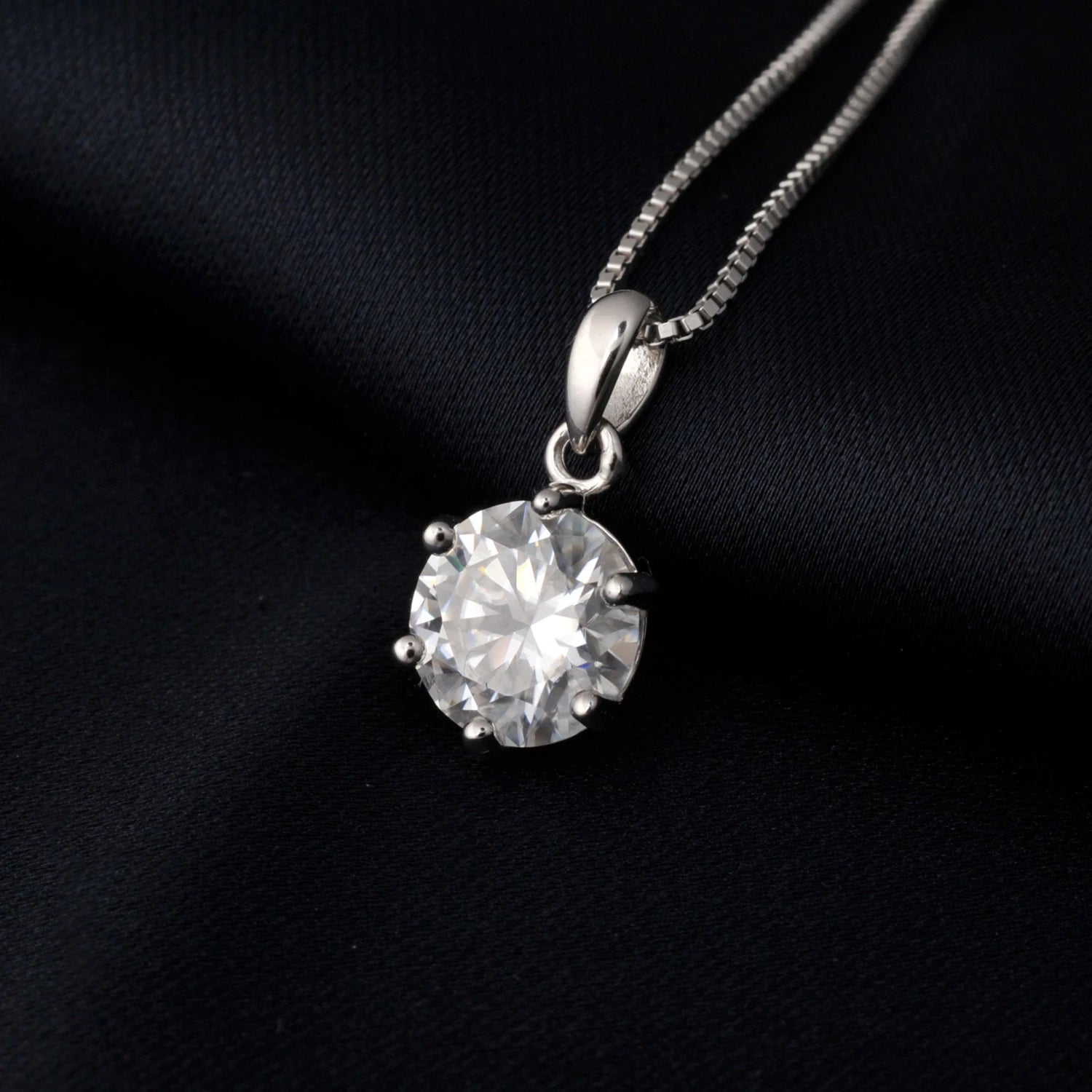 Silver necklace with a round moissanite pendant on a black background