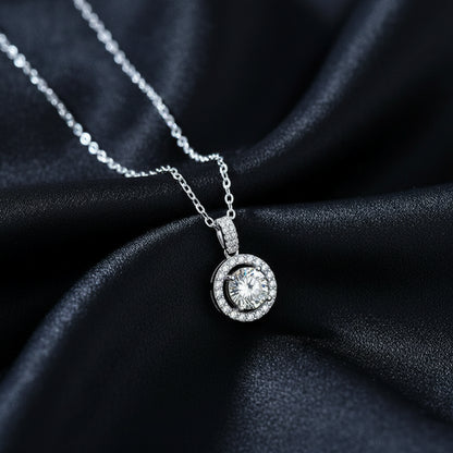 Ava Modus round Moissanite halo pendant displayed on draped black silk to showcase the rhodium finish
