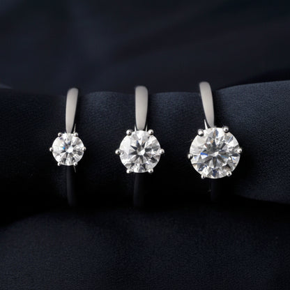 Three different sizes of moissanite rings on a black background