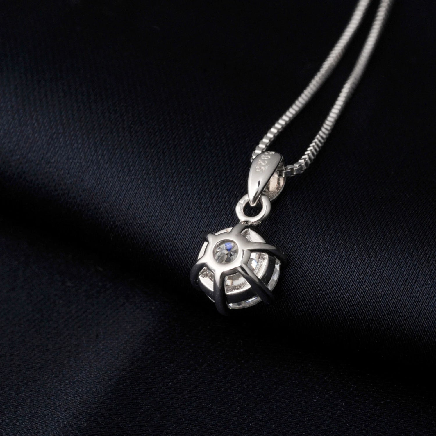 Silver pendant necklace from the back on a black fabric background