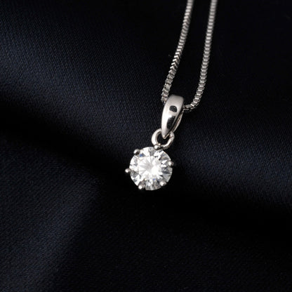 Silver necklace with a round moissanite pendant on a black fabric background