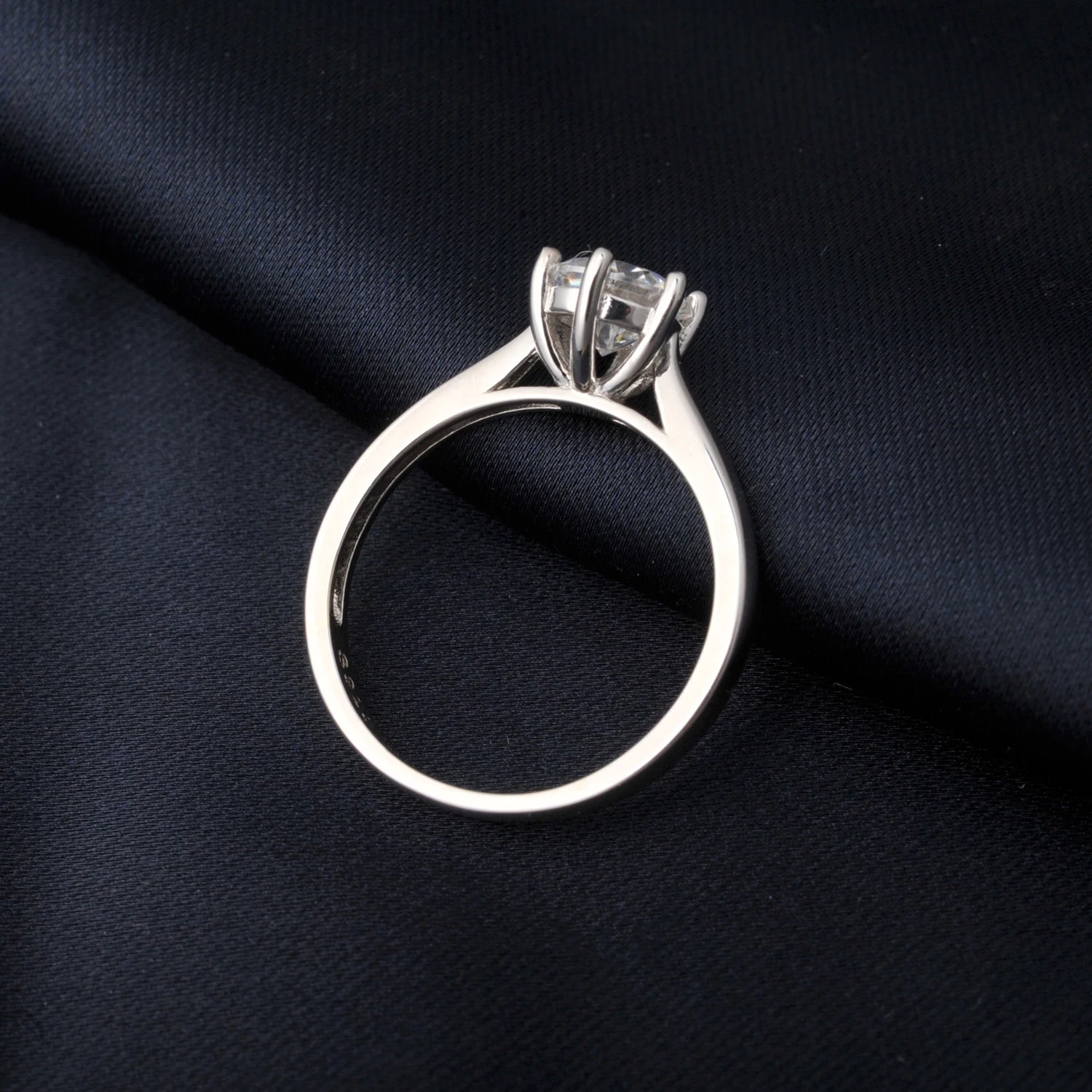 Silver ring with a moissanite on a black fabric background