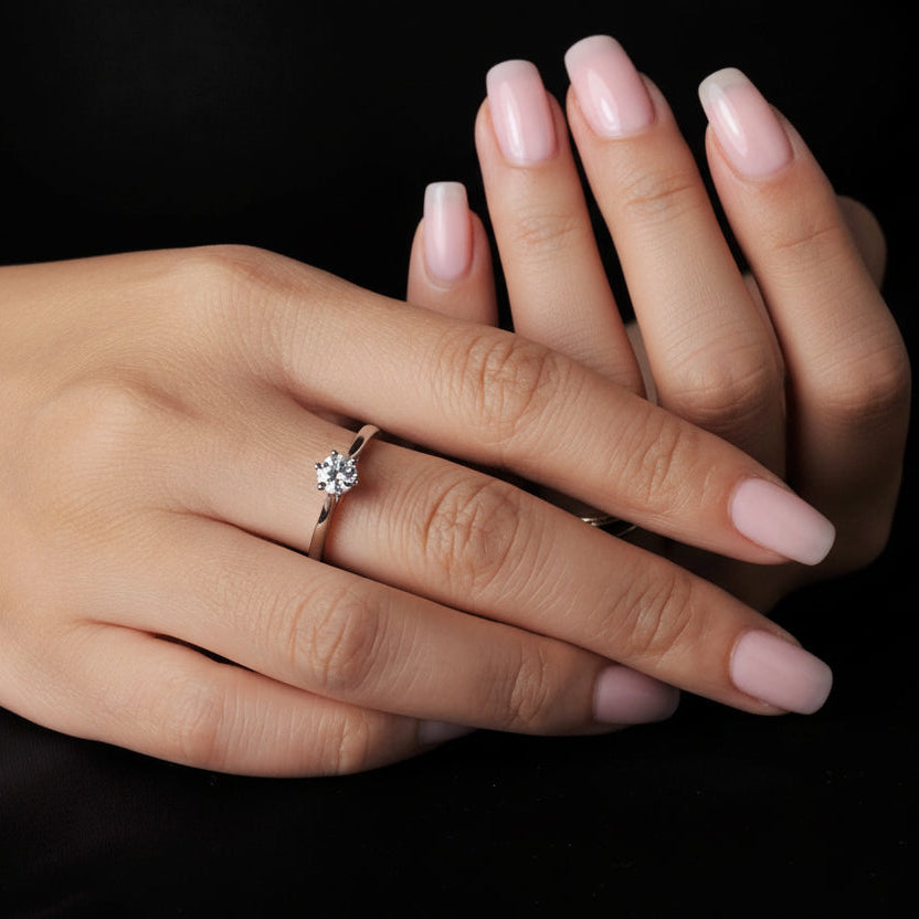 Hand wearing a moissanite ring on a black background