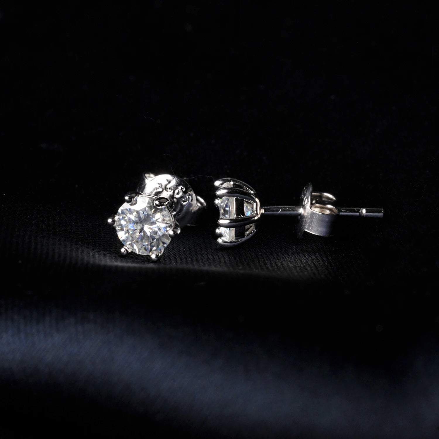 Silver moissanite stud earrings on a black background