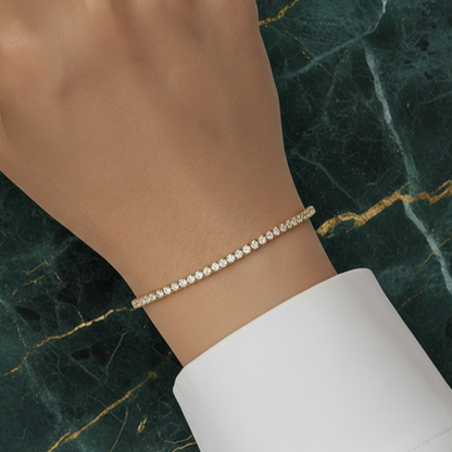 Model's wrist wearing the 14K Gold Glimmer Bolero Bracelet against a green marble background for a luxury aesthetic