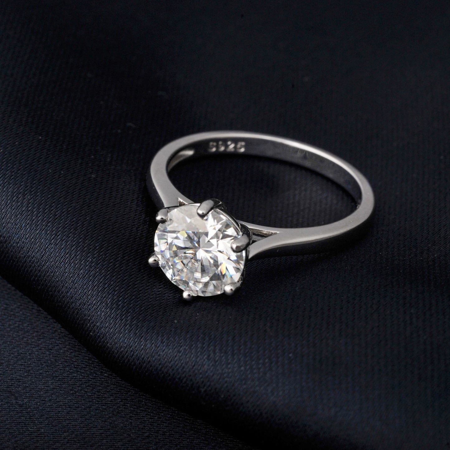 Silver ring with a large moissanite on a black fabric background