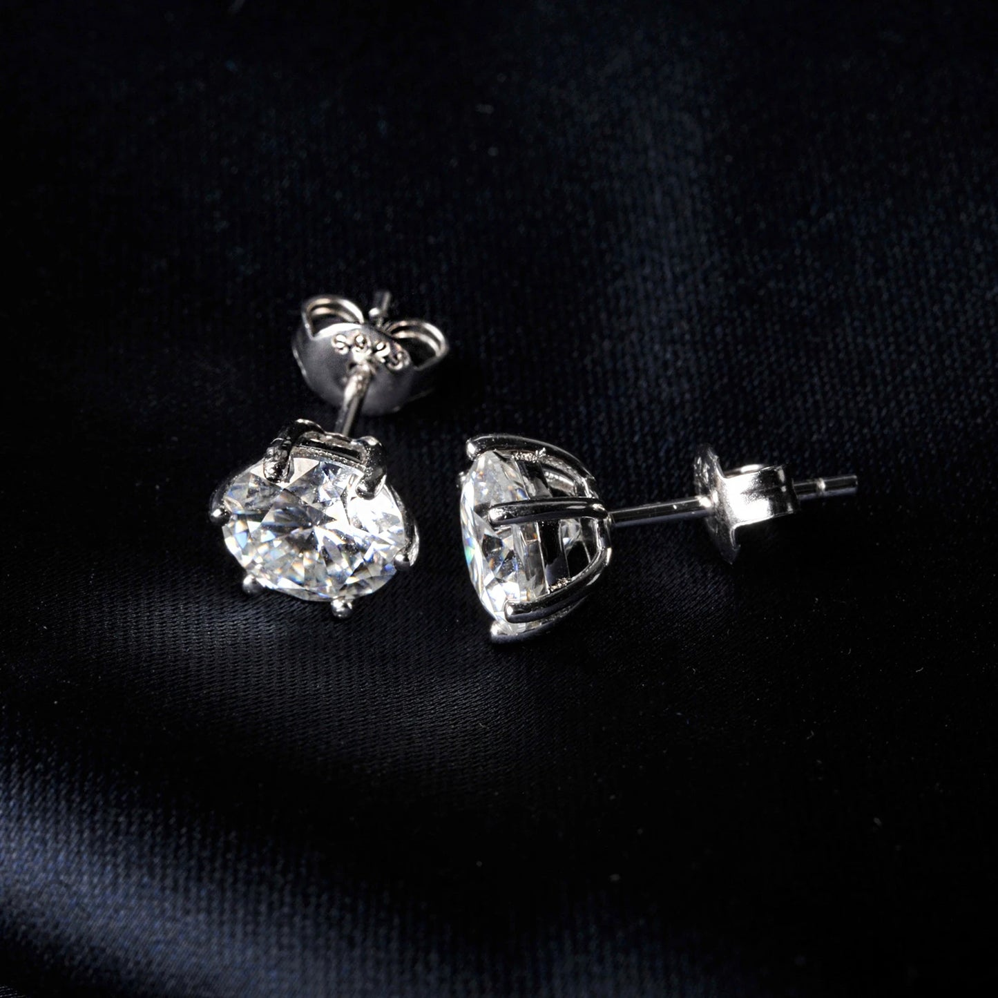 Pair of silver moissanite stud earrings on a black background