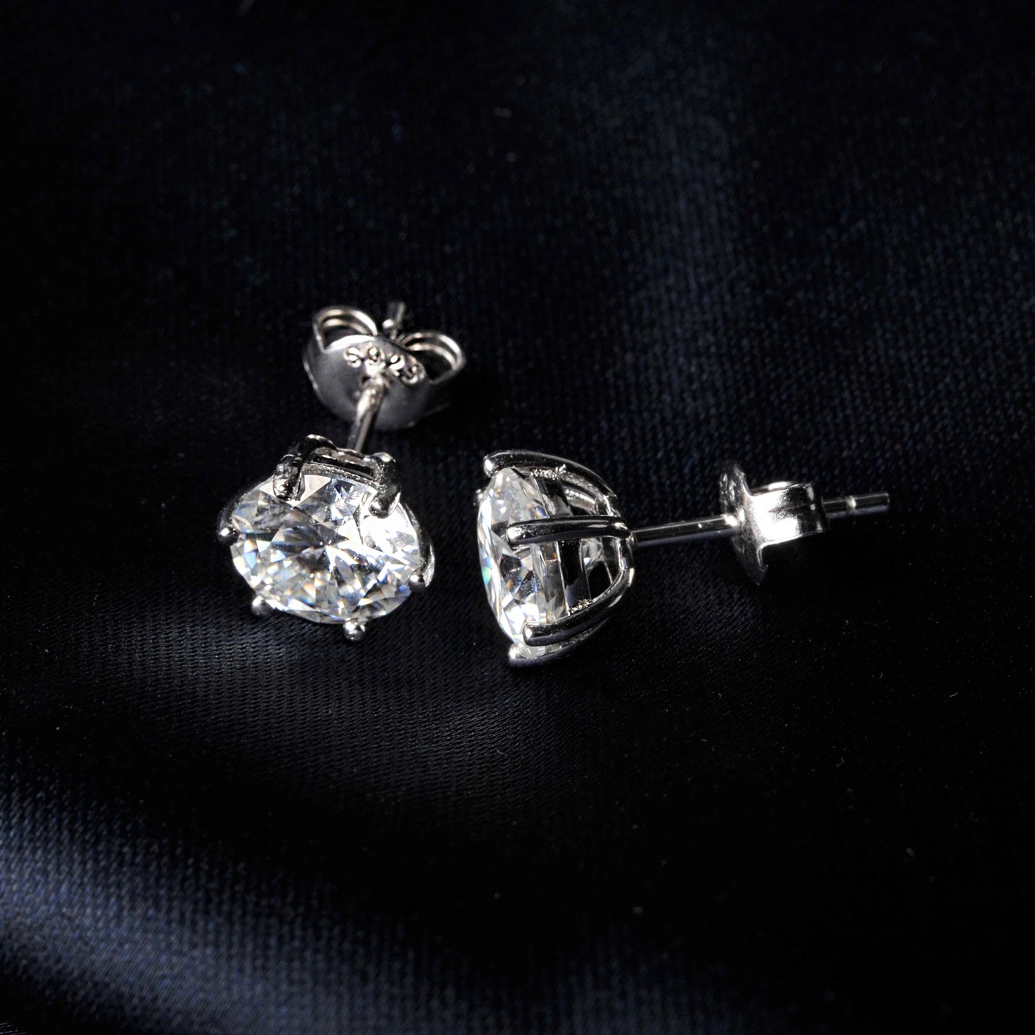 Pair of silver moissanite stud earrings on a black background