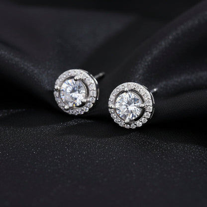 Artistic shot of the Pure Halo Studs nestled in black silk folds, highlighting the brilliant round-cut center stone