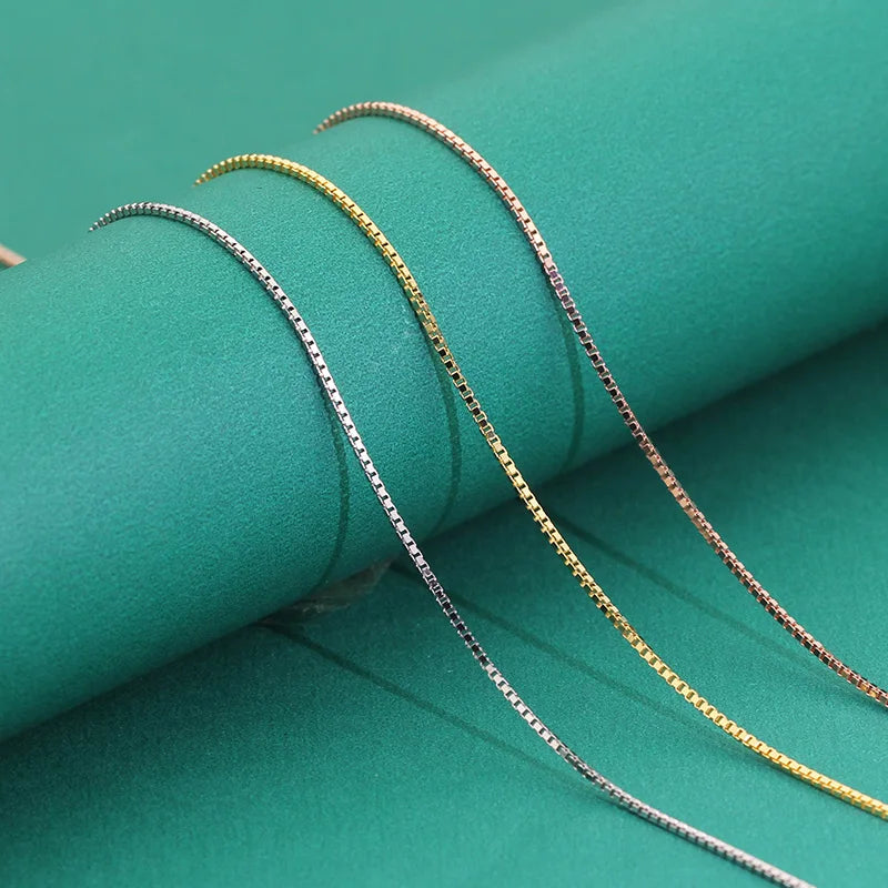 Sleek silver, gold, and rose gold box chains displayed together on green background.