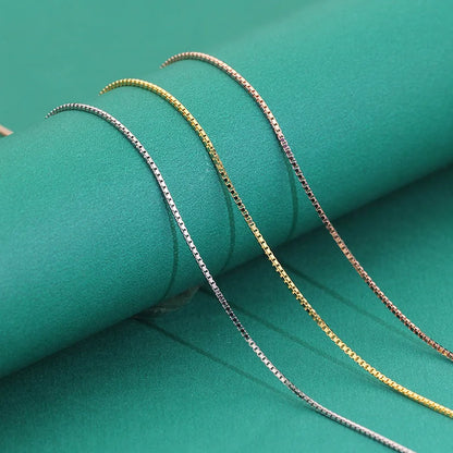 Sleek silver, gold, and rose gold box chains displayed together on green background.