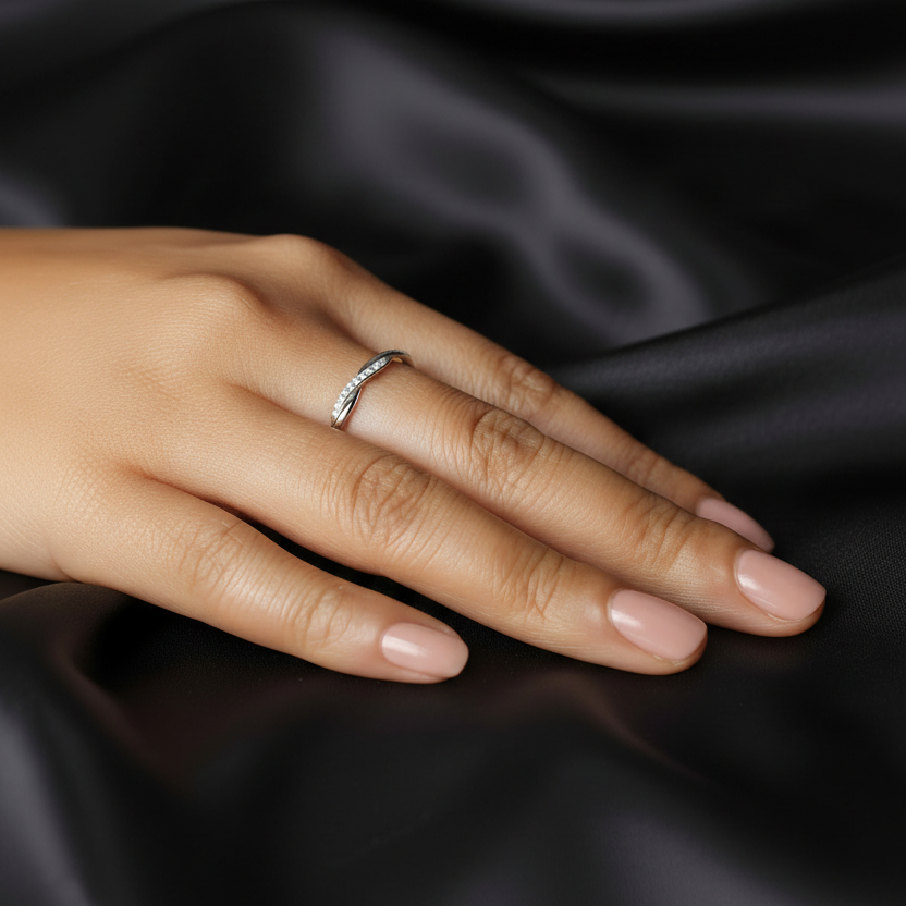Hand wearing a ring on black satin fabric