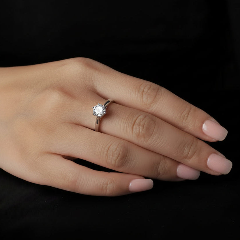 Hand wearing a moissanite ring on a black background