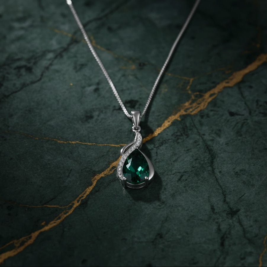Silver pendant with a green gemstone on a dark textured background