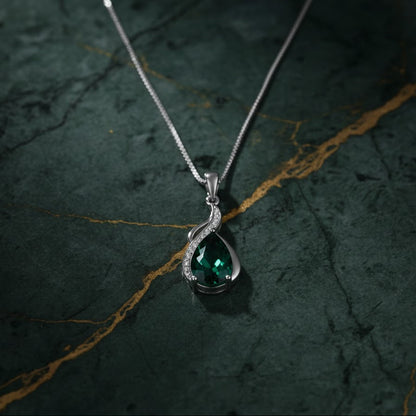 Silver pendant with a green gemstone on a dark textured background
